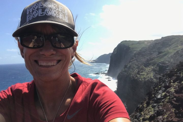 a person wearing a hat and sunglasses in front of a mountain